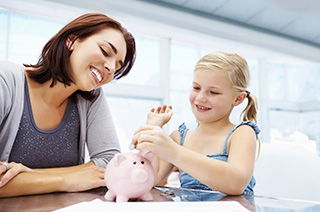 Mother/daughter putting coins in piggy bank